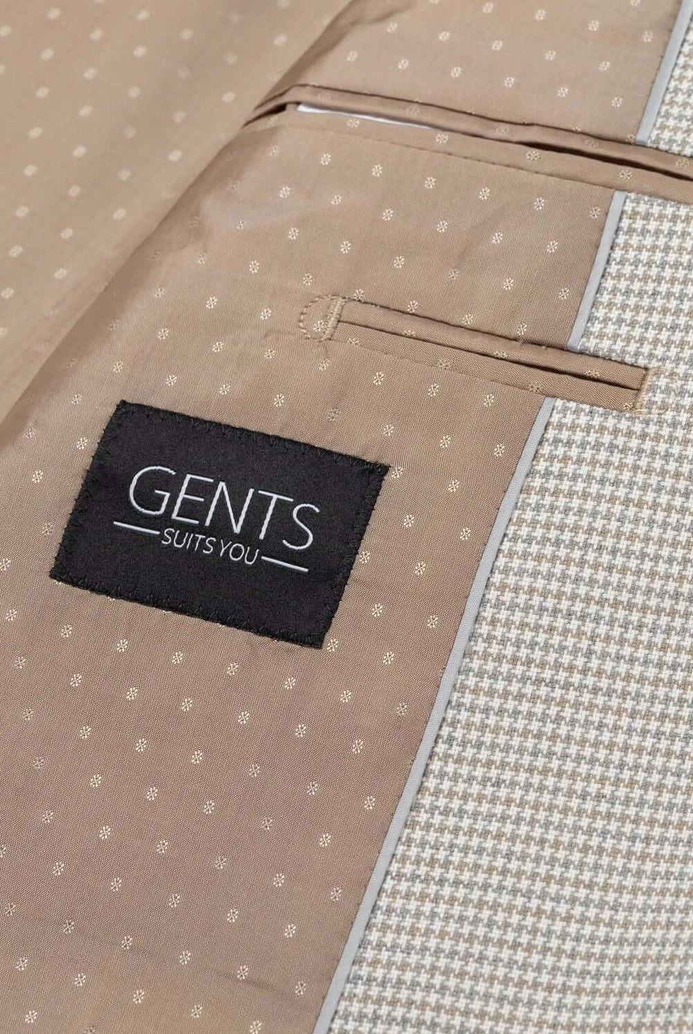 Detail of GENTS Suits You branding on a beige jacket with a textured interior and pocket.