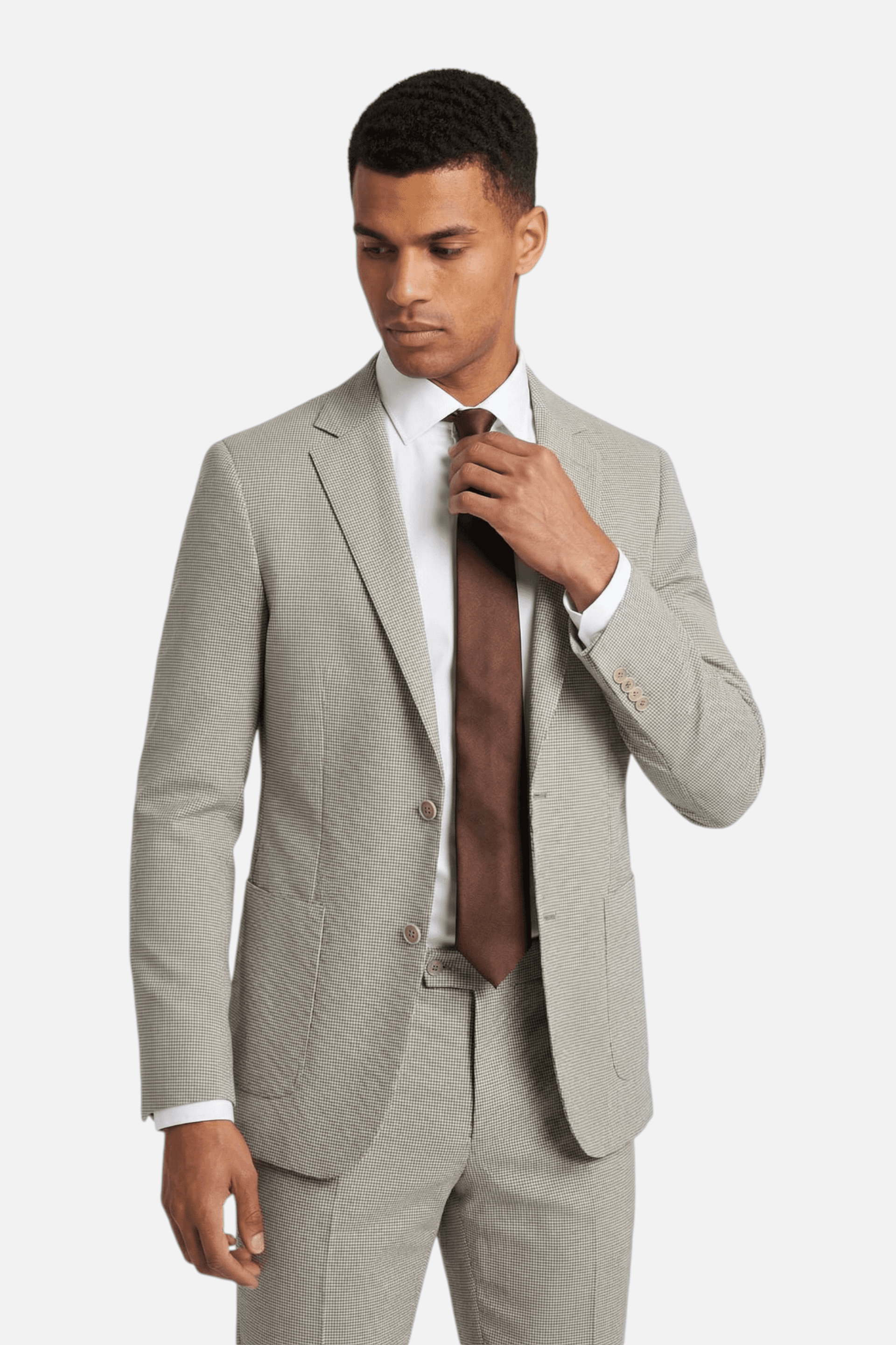 Homme portant un colbert pied-de-poule beige avec cravate marron.