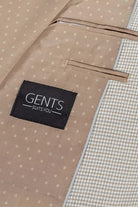 Detail of GENTS Suits You branding on a beige jacket with a textured interior and pocket.